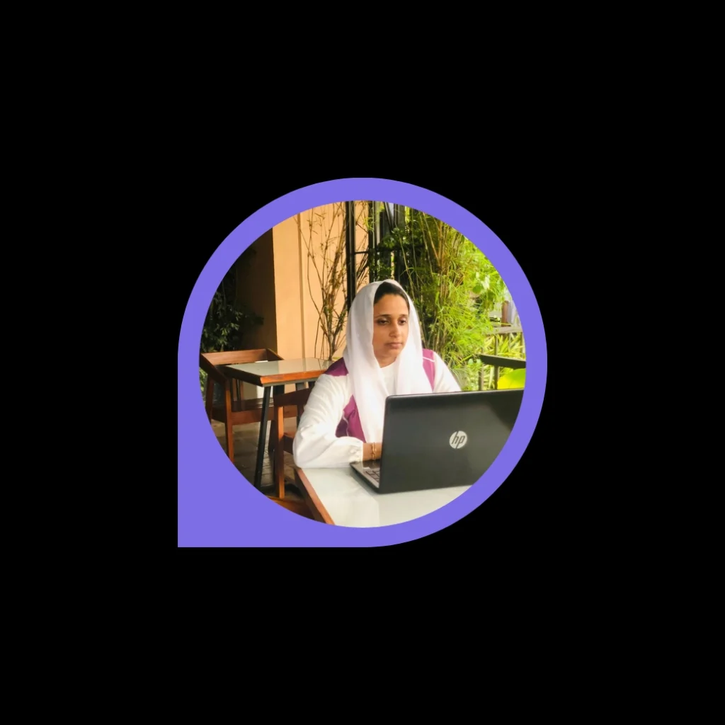 Digital marketing freelancer in Calicut working remotely on an HP laptop at an outdoor café, wearing a white and pink outfit with a headscarf, surrounded by greenery.